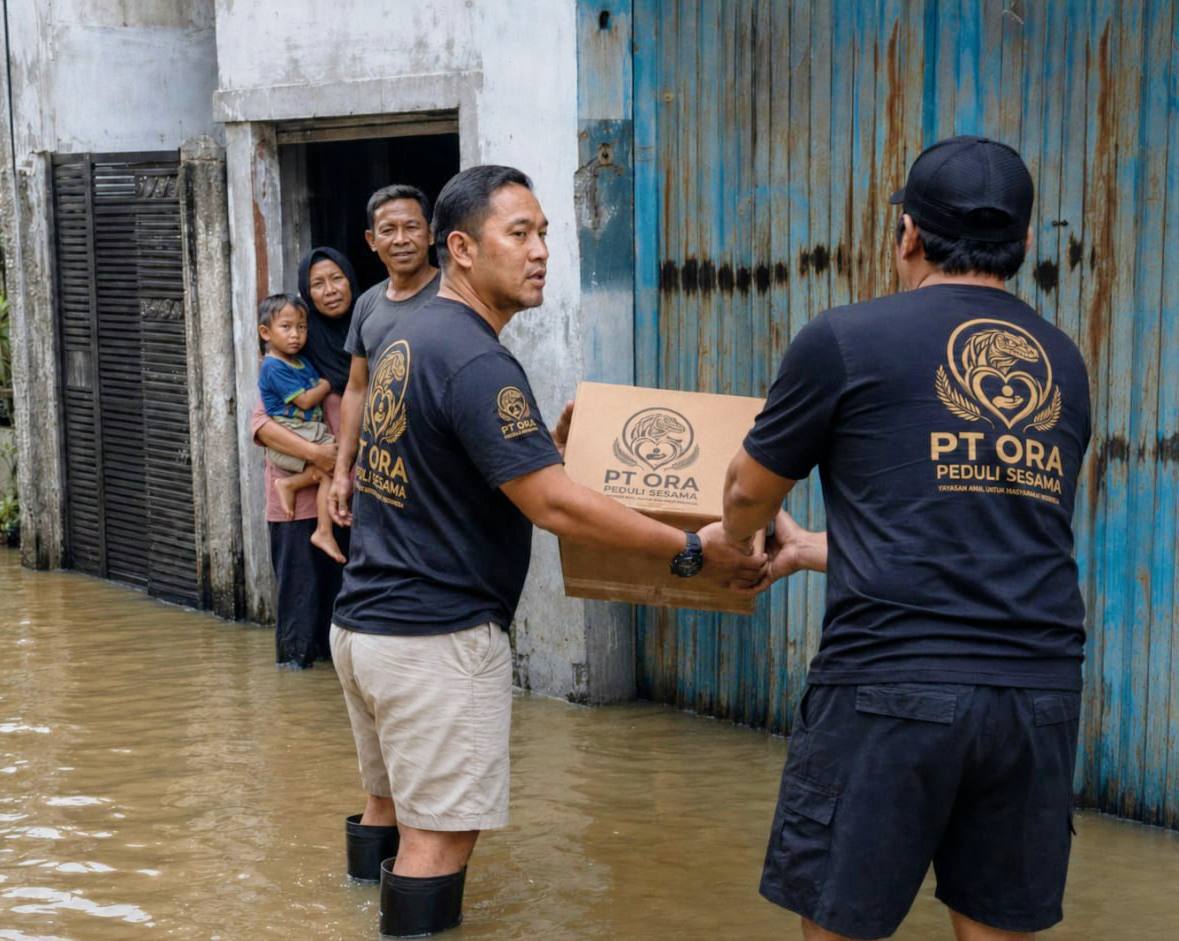 Orang membawa kotak bantuan di depan rumah yang tergenang